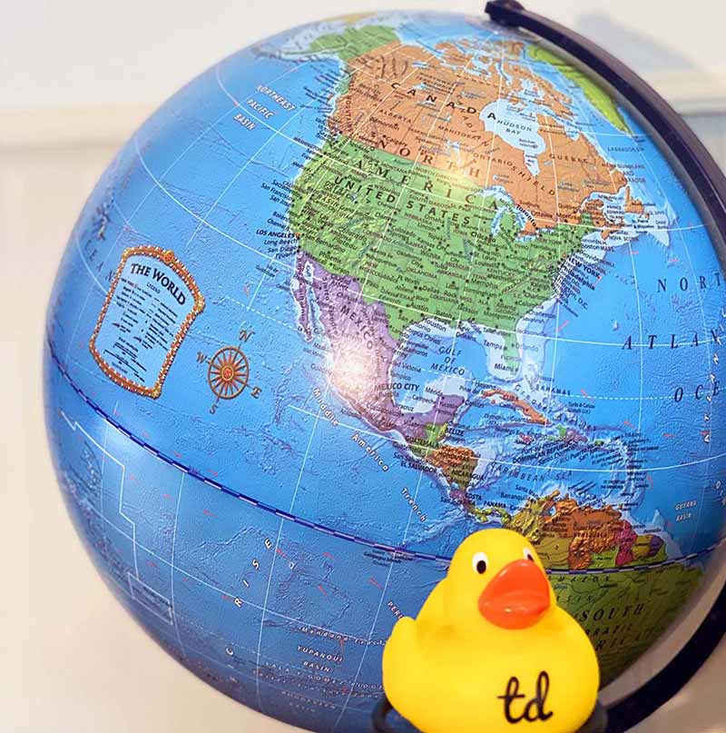 Test Double rubber duck programmer in front of a globe