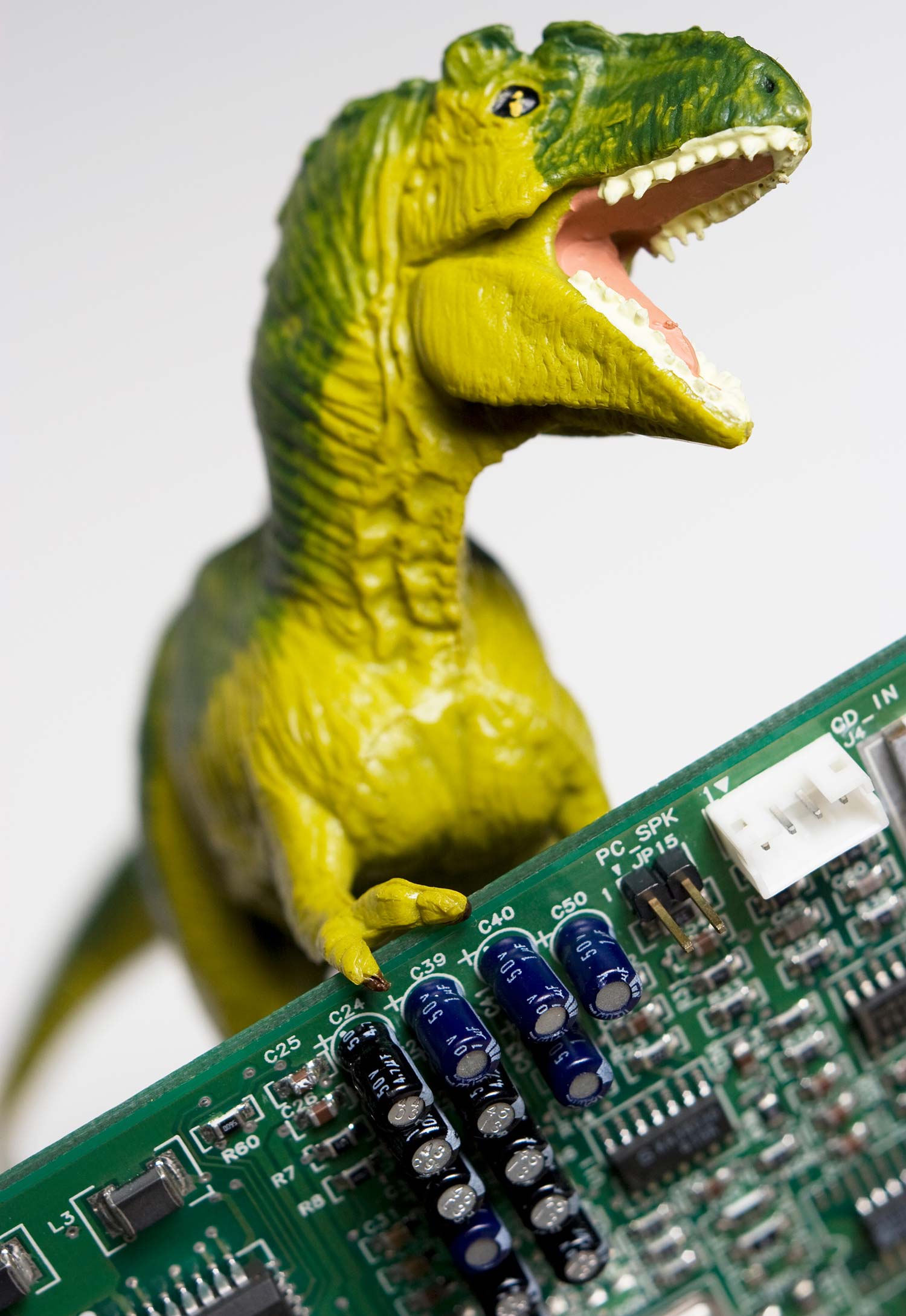 Green dinosaur toy attacking a motherboard