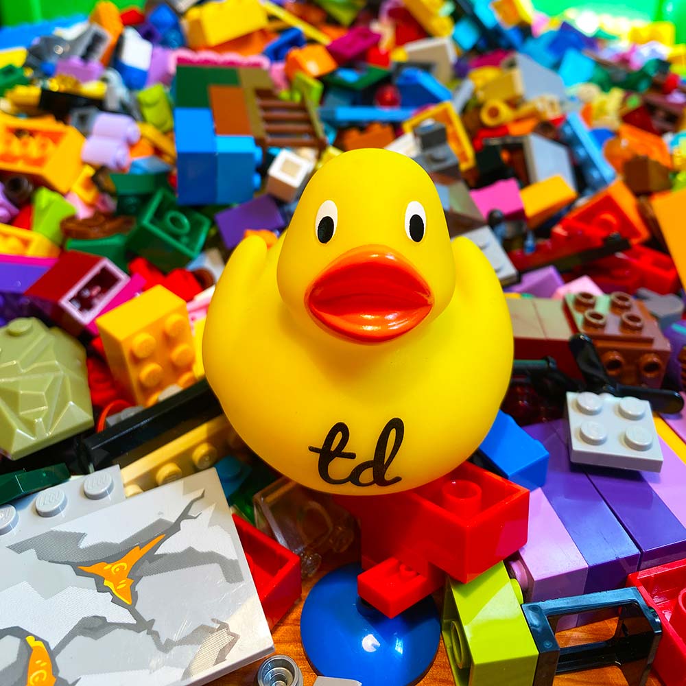 Test Double logo rubber duck programmer sitting on a messy pile of LEGO bricks
